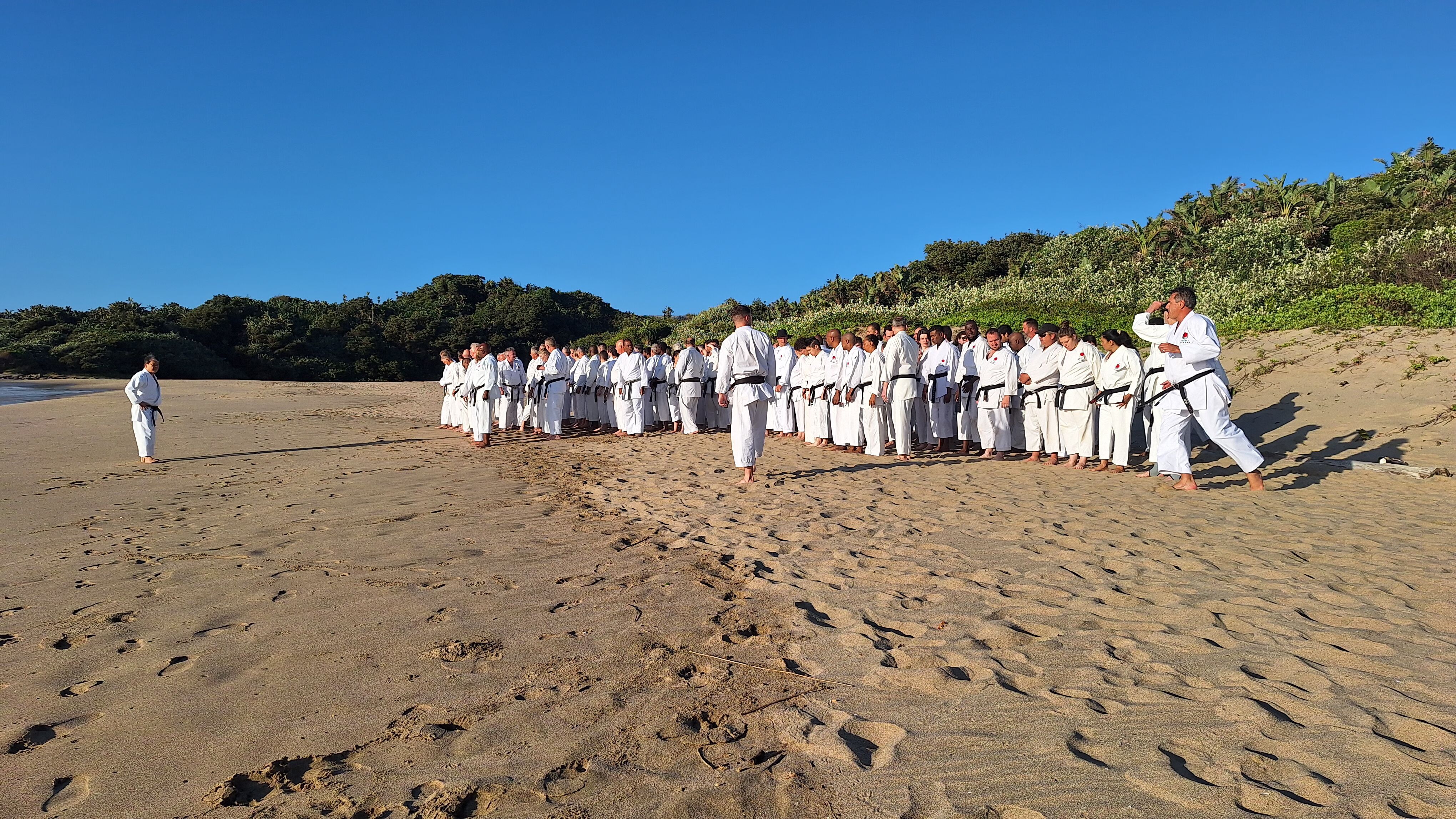 Karateka lined up on the beach for training during the December 2025 gasshuku
