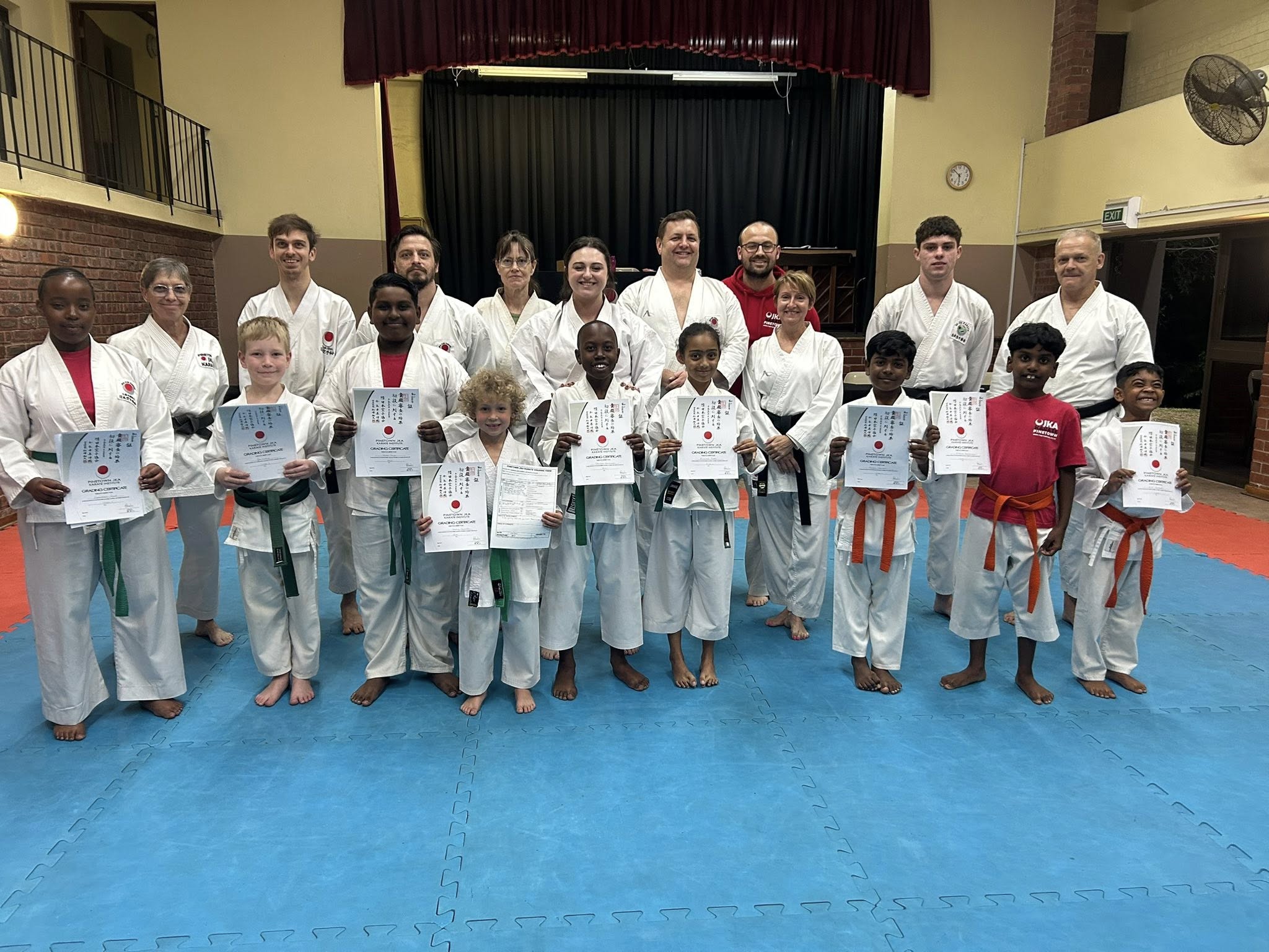 Students and instructors posing with grading certificates in the dojo, June 2025